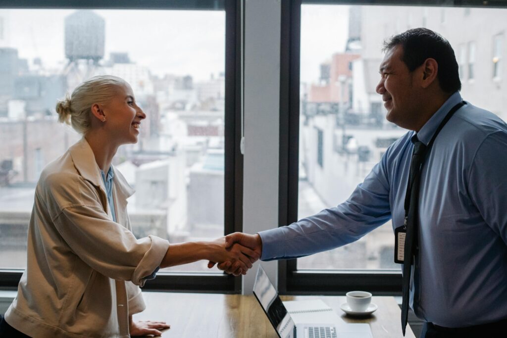 Cheerful colleagues shaking hands while standing at table